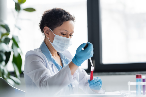 Cientista afro-americano em máscara médica fazendo experiência com equipamentos em laboratório  - Foto, Imagem