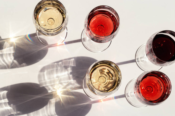 Red, rose and white wine top view in sunlight. Assorted wine in glass. Dark shadows - Foto, Imagen