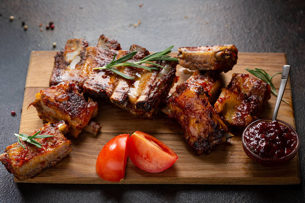 Close up of barbecue smoked ribs with red sauce on wooden cutting board - Photo, Image