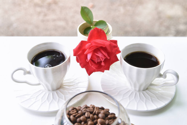 Two cups of coffee, coffee beans and a red rose on a white table - Photo, Image