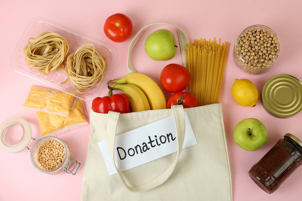 Έννοια της δωρεάς με φαγητό σε ροζ φόντο - Φωτογραφία, εικόνα
