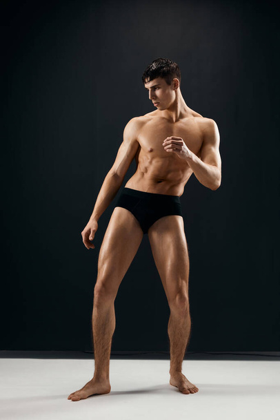 sporty man in black panties with naked muscular body dark background - Foto, immagini