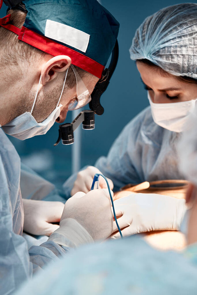Chirurg assistent voedt coagulator, plastische chirurgie, professionele artsen, close-up. - Foto, afbeelding