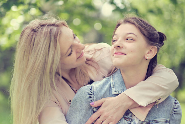 Eine glückliche Mutter mit ihrer Tochter, die im Sommer einen Teenager umarmt. Fürsorgliche glückliche Mutter genießen Tag mit Teenager-Mädchen Kind, lachen Spaß haben. Mutter gibt ihrer Tochter Rat. - Foto, Bild