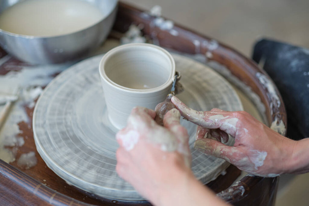 Zbliżenie kobiece ręce zrobić naczynia z gliny. kobiece ręce pracujące nad kołem garncarskim. Mistrz garncarstwa pracuje w warsztacie. - Zdjęcie, obraz