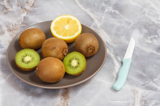 Kiwi enteros y en rodajas de frutas y limón en la mesa de piedra - Foto, imagen