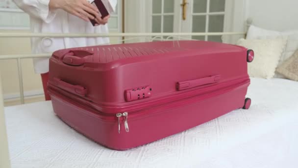 Μια γυναίκα ανοίγει στο κρεβάτι μια μεγάλη ροζ βαλίτσα με ρούχα. - Πλάνα, βίντεο