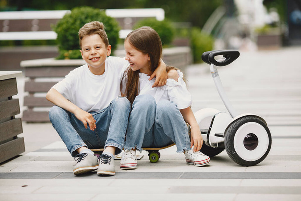 Children learn to ride hoverboard in a park on sunny summer day - Foto, Imagem
