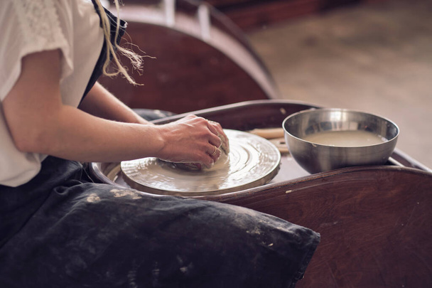 Close up female hands make dishes from clay. woman hands working on potters wheel. The master potter works in a workshop - Fotografie, Obrázek