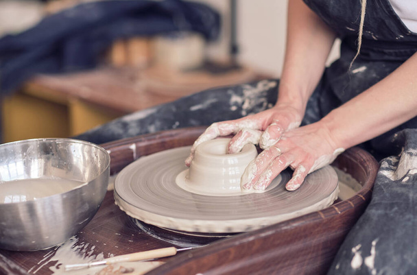 Близько до жіночих рук роблять посуд з глини. жіночі руки працюють на гончарному колесі. Майстер гончар працює в майстерні
 - Фото, зображення