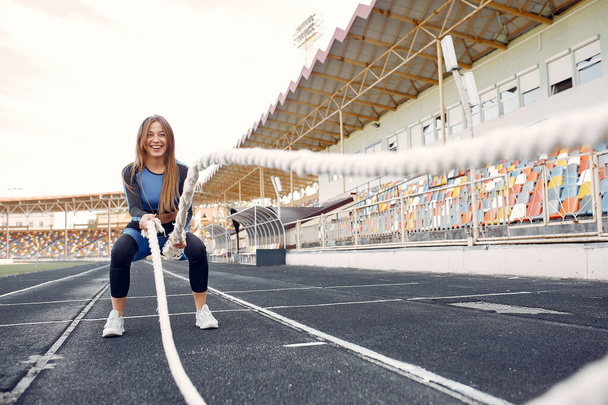 Sports girl in a blue uniform training at the stadium with rope - Foto, imagen