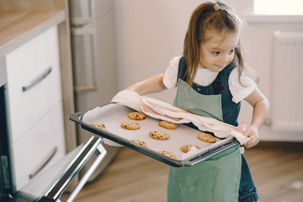 Little girl pulls a cookie from the oven - Φωτογραφία, εικόνα