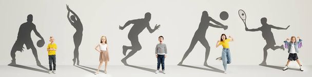Collage. Dreams about big and famous future. Conceptual image with little boys and girls and shadows of fit professional sportsmen on light gray background - Фото, изображение