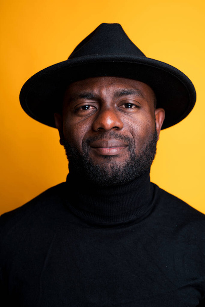 Portrait of an African American man in a black turtleneck and hat. Isolated on yellow background - Foto, immagini