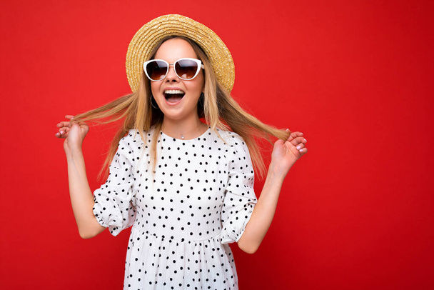Attractive positive amazing young blonde woman wearing everyday stylish clothes and modern sunglasses isolated on colorful background wall looking at camera - Zdjęcie, obraz