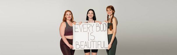 Test pozitív sportnők gazdaság placard minden test gyönyörű elszigetelt szürke, banner  - Fotó, kép