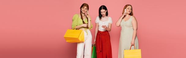Body positive women with shopping bags talking on smartphones on pink background, banner  - Fotografie, Obrázek