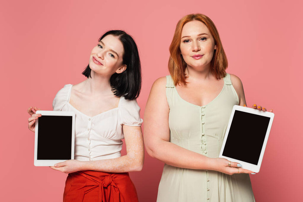 Body positive women holding digital tablets with blank screen on pink background  - Zdjęcie, obraz