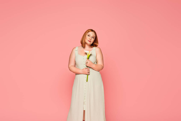 Pretty plus size woman holding calla lily isolated on pink  - Fotografie, Obrázek