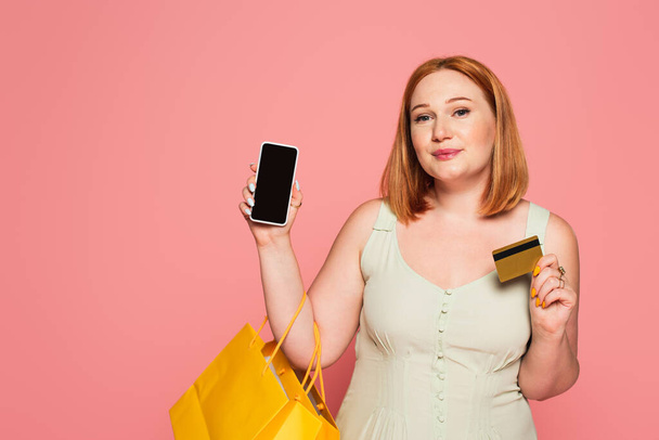 Body positive woman with shopping bags, smartphone and credit card isolated on pink  - Foto, Bild