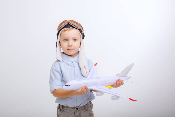 małego chłopca w czapce pilota i z samolotem na białym tle - Zdjęcie, obraz