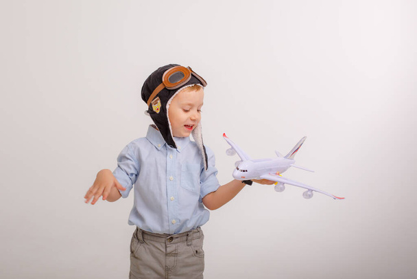 malý chlapec v klobouku pilota a s letadlem na bílém pozadí - Fotografie, Obrázek