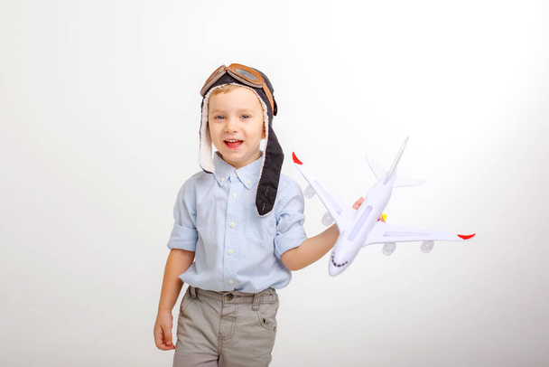 a little boy in a pilot's hat and with an airplane on a white background - Photo, Image