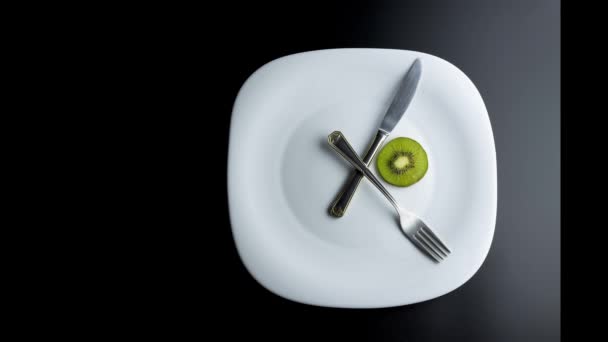 Stop-Motion einer Platte, die eine Uhr mit den Zeigern einer Gabel und eines Messers simuliert, das Essen zeigt, Konzept des intermittierenden Fastens - Filmmaterial, Video