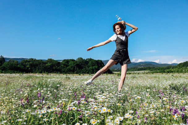 Güzel, genç, mutlu bir kadın papatya tarlasında koşuyor. - Fotoğraf, Görsel