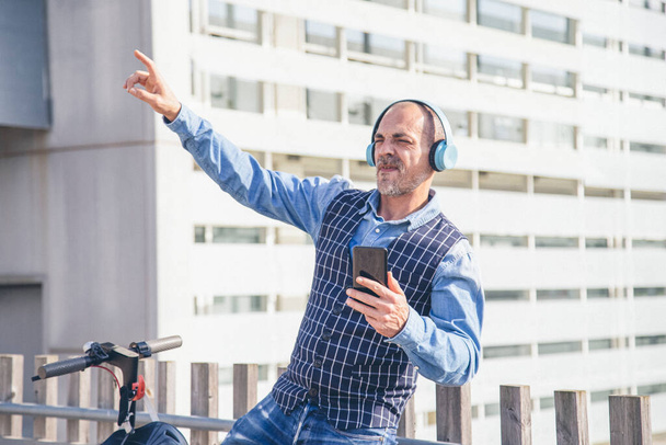Unbekümmerter Geschäftsmann mit Kopfhörern, der glücklich Musik hört - Foto, Bild