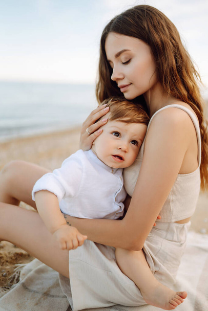 Mother with a child have fun outdoors playing games love each other. Young family with little baby boy spending time together on the beach. Family, childhood, active lifestyle concept. - Foto, afbeelding