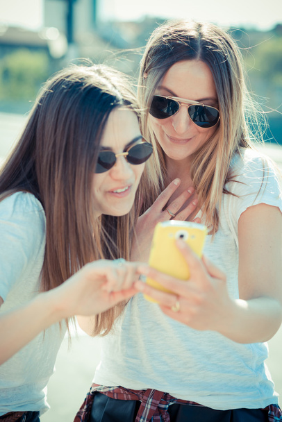 две красивые молодые женщины с помощью смартфона
 - Фото, изображение