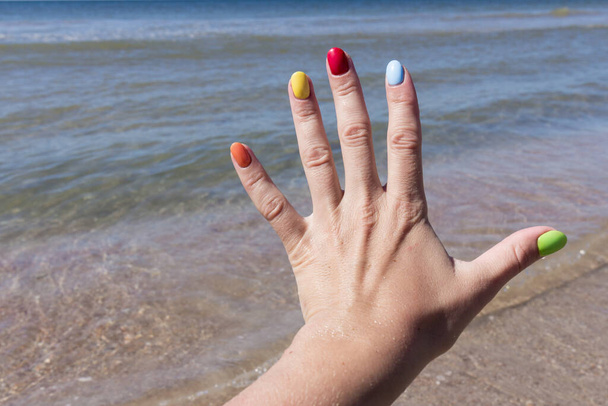 Barevné nehty na písečné pláži. Barevný lak na nehty. koncepce letního odpočinku - Fotografie, Obrázek
