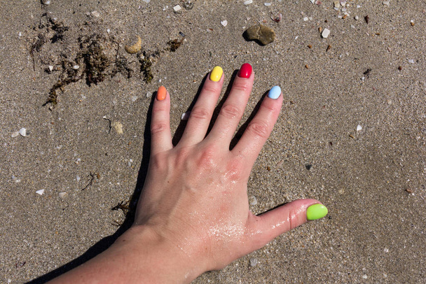 Barevné nehty na písečné pláži. Barevný lak na nehty. koncepce letního odpočinku - Fotografie, Obrázek