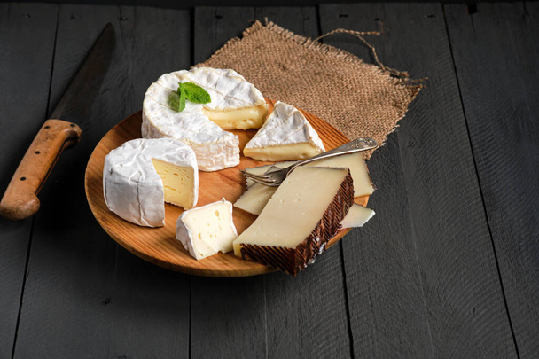 Variety of French and Spanish cheeses on black wooden background - Φωτογραφία, εικόνα