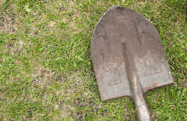 Старая грязная лопата крупным планом на траве. Вид сверху, летний день - Фото, изображение
