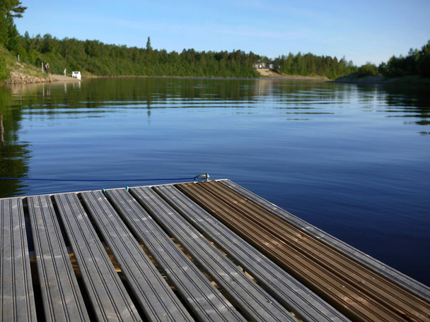 Muelle de madera en el río ivalo claro a medianoche tiempo finland scandinavia - Foto, Imagen
