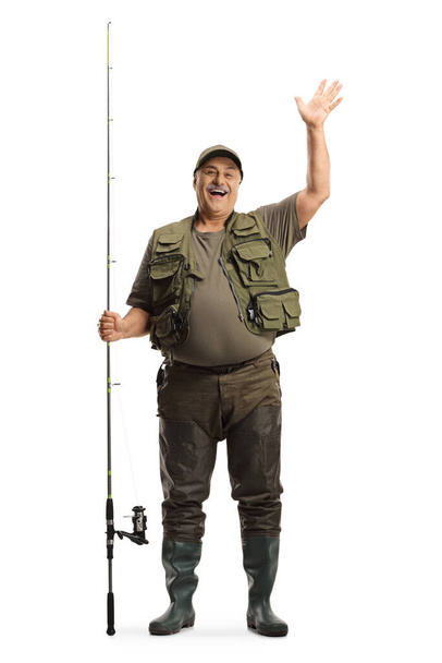 Full length portrait of a fisherman with a fishing rod standing and waving isolated on white background - Valokuva, kuva