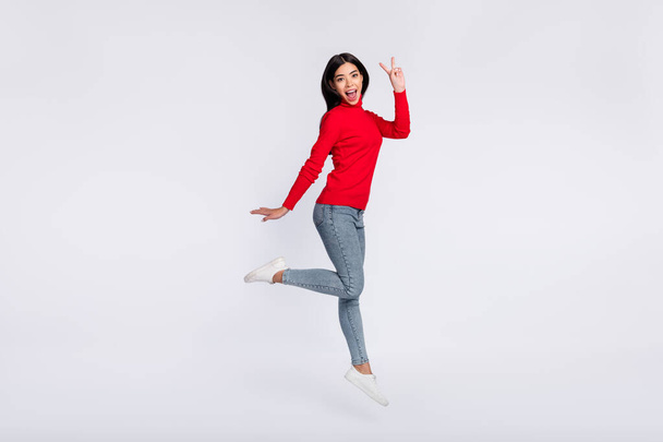 Full size photo of happy excited pretty woman jumping showing v-sign symbol isolated on grey color background - Photo, Image