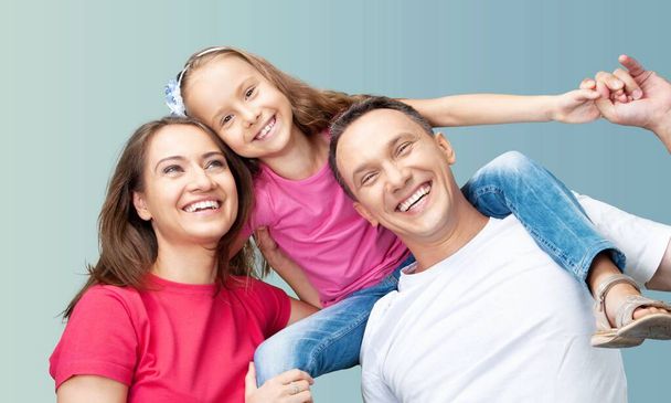 Laughing funny young happy parents mom dad with child kid on blue color background - Фото, зображення