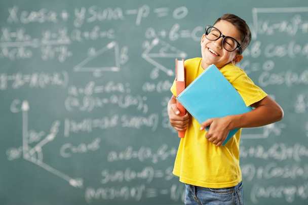 Happy funny cute little child boy in student uniform holding books, school education - Фото, зображення
