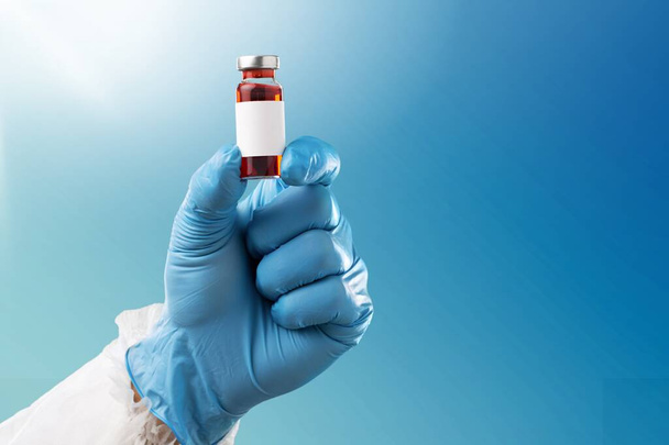 Coronavirus Vaccine in a glass bottle in the hand of the doctor on the background. - Foto, Imagen