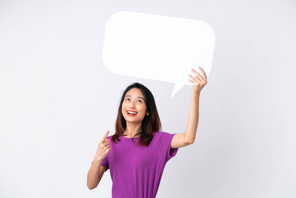 Young Vietnamese woman isolated on white background holding an empty speech bubble and pointing it - Photo, Image
