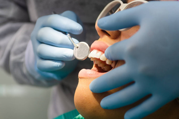 Νεαρή γυναίκα ασθενής λαμβάνει οδοντιατρική παρακολούθηση στο οδοντιατρικό γραφείο. - Φωτογραφία, εικόνα