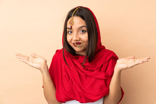 Young Indian woman isolated on beige background having doubts - Foto, Bild