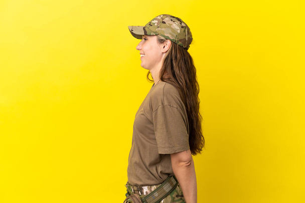 Military caucasian woman with dog tag isolated on yellow background laughing in lateral position - Photo, Image