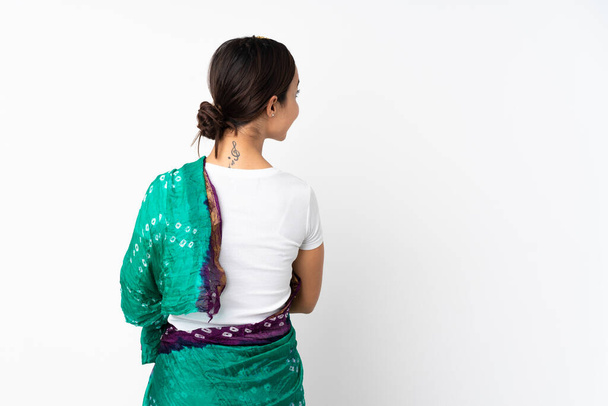 Молодая индийская женщина изолированы на белом фоне в задней позиции и глядя на сторону - Фото, изображение