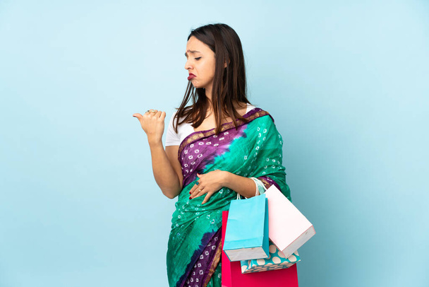 Jovem indiana com sacos de compras infelizes e apontando para o lado - Foto, Imagem
