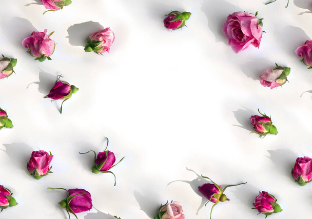 Frame of flowers pink roses buds on a light background with space for text. Top view, flat lay - Photo, Image