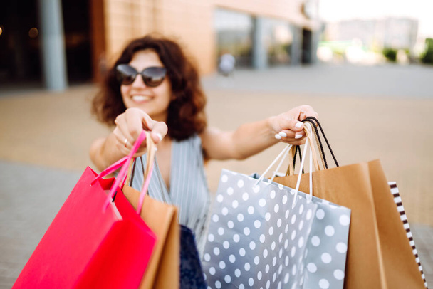 Shopping bags in the woman hands. Young woman after shopping. Sale, shopping, tourism and happy people concept. - Фото, изображение